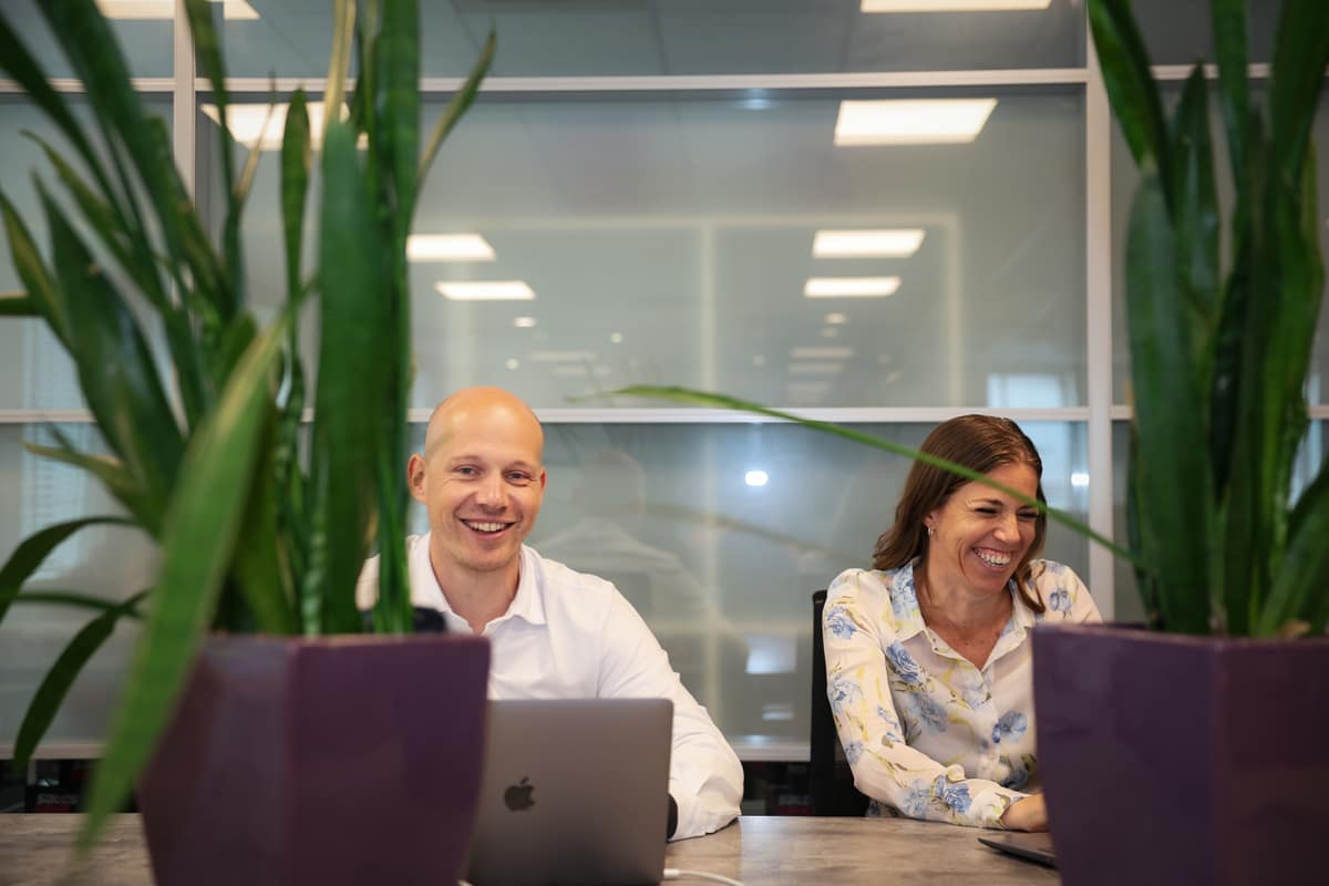 Twee collega’s lachend achter hun laptop