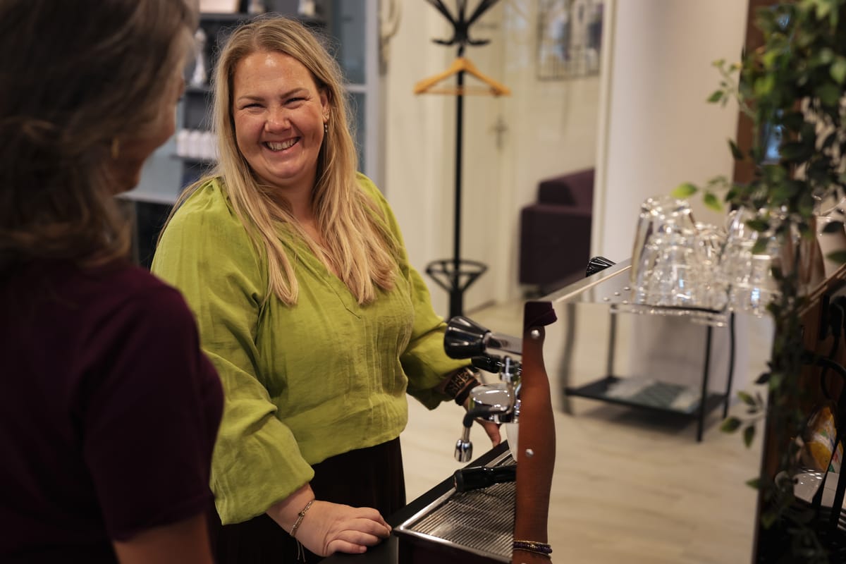 Lachende collega achter de koffiemachine